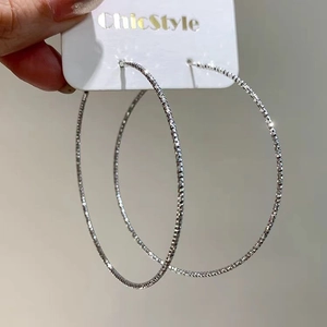Silver textured large hoop earrings with sparkling diamond-cut finish on display card