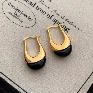 Dettaglio di orecchini a goccia a U con base in oro 18K e ciondoli neri lucidi