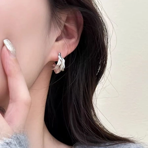 Modern irregular wave silver earrings with textured finish on a female model