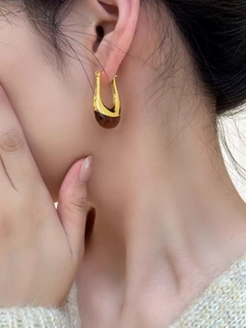 Dettaglio orecchino in oro 18K a forma di U con pendente in resina ambra su modella