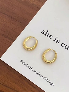 Detail shot of golden hoop earrings with spiral texture on a display card