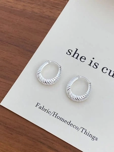 Macro view of silver twisted stripe hoop earrings on a minimalist display card