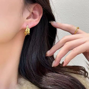 Irregular gold pleated earrings and twisted ring set on model with matte finish