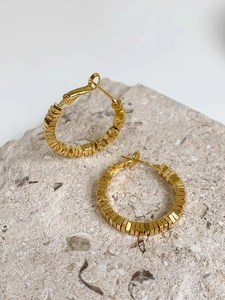 Detailed view of gold multi-layered square block hoop earrings on a stone surface