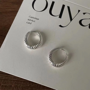 Macro detail of silver twisted croissant hoop earrings with a polished metallic finish