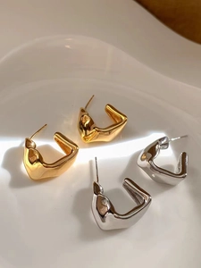 Chic irregular geometric metal earrings in gold and silver on a white porcelain tray