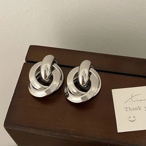 Close-up of polished silver interlinked geometric hoop earrings on a wooden surface