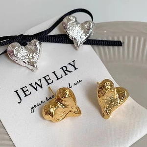 Unregelmäßige Lava-Herzohrringe in Gold und Silber auf weißer Schmuck-Displaykarte