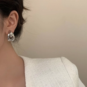 Modern silver geometric multi-layer hoop earrings shown on a model in profile view