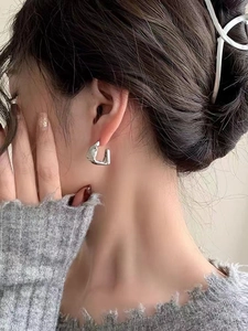 Macro view of minimalist silver geometric square hoop earrings worn on a female model