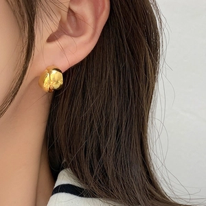 Close-up of polished gold geometric hoop earrings showing glossy mirror finish on model