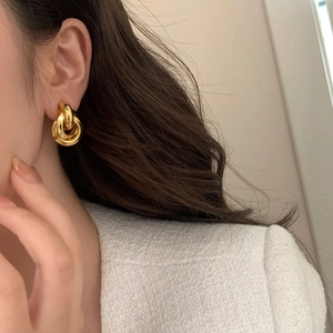 Minimalist gold-plated interlocking triple hoop earrings shown worn on ear by model
