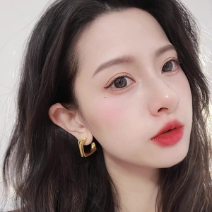 Minimalist gold heart stud earrings on model showcasing polished geometric fashion style