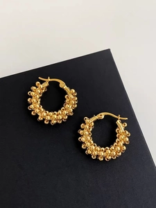 Detailed view of gold textured hoop earrings with a beaded sphere design on a black box