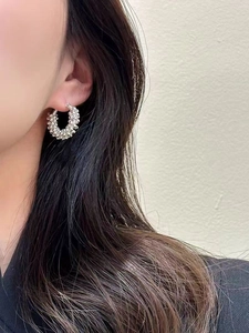 Detailed view of silver hoop earrings with textured metal beads worn by a model