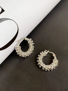 Macro detail of silver beaded textured hoop earrings on premium leather background