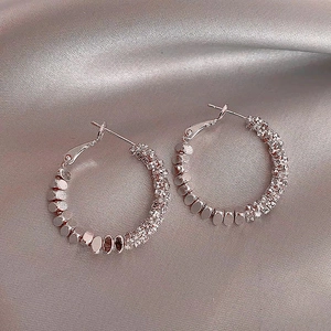 Détail de créoles en argent avec perles polies et pierres de zircone scintillantes