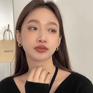 Golden striped metal C-shaped earrings worn by a model for a chic luxury look