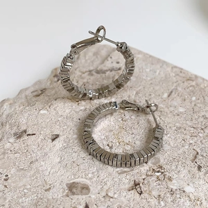 Modern silver multi-layered square hoop earrings displayed on a natural stone base