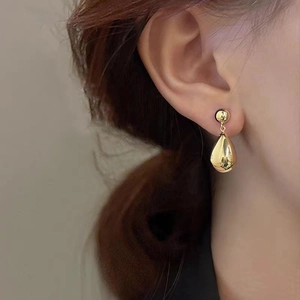 Boucles d'oreilles goutte en or poli sur modèle avec un design géométrique minimaliste