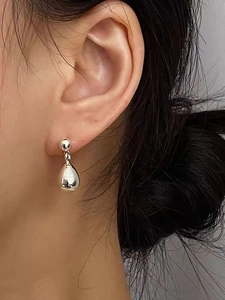 Gros plan de boucles d'oreilles goutte d'argent poli avec fini miroir sur un mannequin