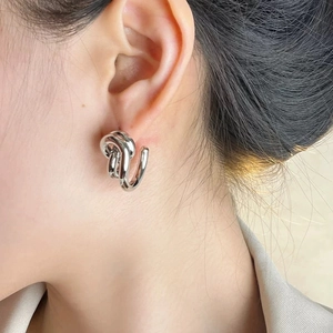 Minimalist silver S925 geometric irregular knot earrings worn by a model on plain background