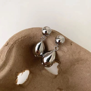Gros plan détaillé de boucles d'oreilles goutte argentées avec finition miroir polie