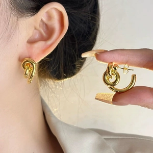 Detail view of gold twisted double loop earrings showing modern knotted metal texture