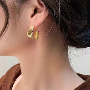 Irregular gold geometric earrings with minimalist molten metal texture worn by a model