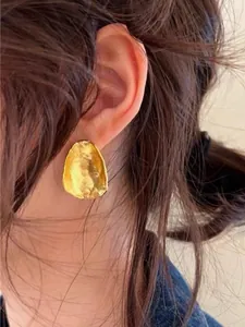 Detailed close-up of golden irregular geometric stud earrings with hammered texture