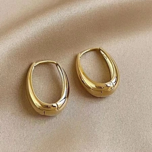 Elegant gold chunky hoop earrings with a polished finish on champagne silk background