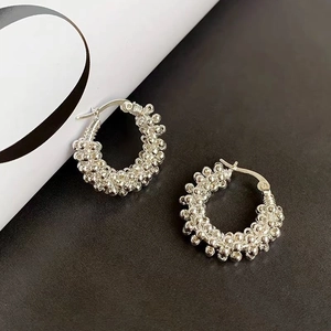 Minimalist silver hoop earrings with textured metal bead surface and glossy finish