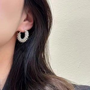Silver beaded hoop earrings with woven texture worn by model for fashion styling