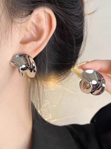 Close-up of silver irregular organic curved earrings featuring a polished mirror finish