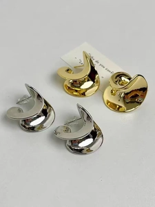 Detailed macro view of spiral C-shaped metal stud earrings in gold and silver finish