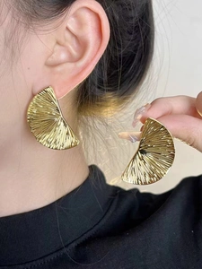 Detail of pleated gold fan earrings on model showing size and elegant texture