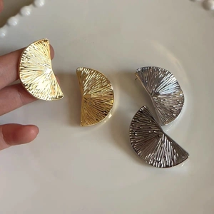 Textured fan-shaped metal earrings in gold and silver with pleated radial patterns