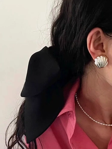 Detail of French vintage shell earrings with black fabric bow and pearl necklace