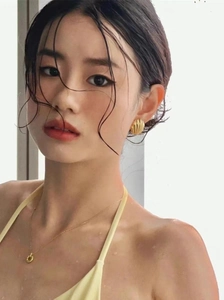 Close-up of elegant gold shell texture earrings and matching necklace on a model