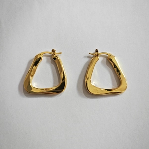 Close-up of golden geometric twisted triangle earrings with high-polish metallic finish