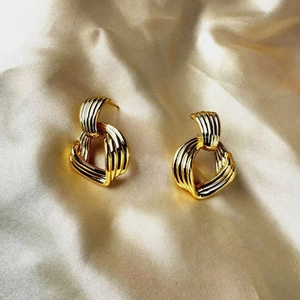 Détail de boucles d'oreilles nœud vintage dorées avec texture métallique rainurée