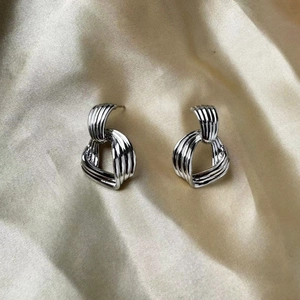 Vue détaillée de boucles d'oreilles nœuds argentés sur satin champagne