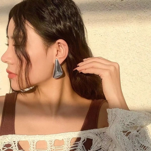 Modern geometric triangle stud earrings in polished silver metal on female model