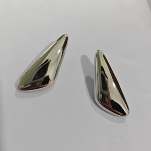 Macro shot of silver teardrop geometric earrings with a polished mirror finish detail