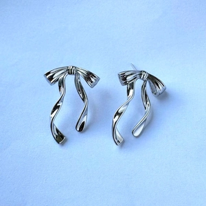 Detailed view of silver butterfly ribbon earrings with a high-polished metallic finish