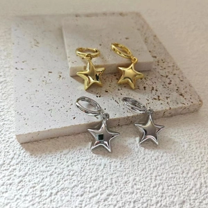 Vista macro di orecchini a cerchio con stella in oro 18K e argento su pietra strutturata
