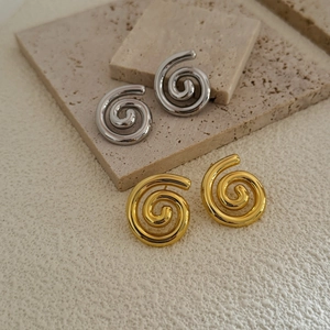 Minimalist spiral hoop earrings in gold and silver finish on stone texture background