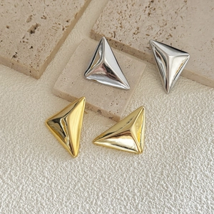 3D geometric triangle stud earrings in gold and silver finish on stone display
