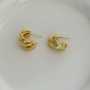 Macro detail of gold-plated C-shaped earrings with a twisted multi-layer spiral design