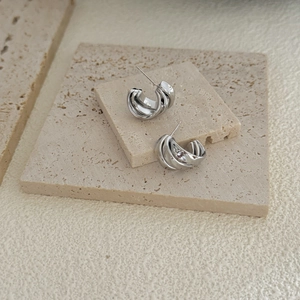 Polished silver geometric triple layered C-shape hoop earrings on travertine stone